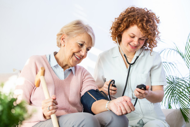 happy-senior-woman-having-her-blood-pressure-measured-nursing-home-by-her-caregiver_1212-2350